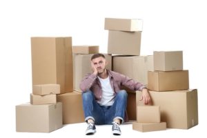 Young man with cardboard boxes on white background