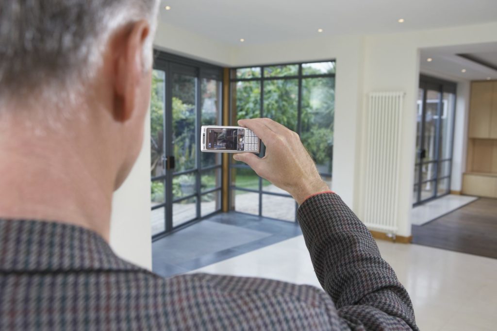 Man Taking Cell Phone Picture of New Home